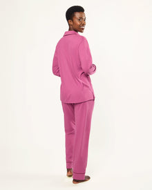 The Women's Pima Pajama Set in Rosewood, featuring a long-sleeve button-up top with a collar and chest pocket, and elastic-waist pants, is shown laid flat on a white background.