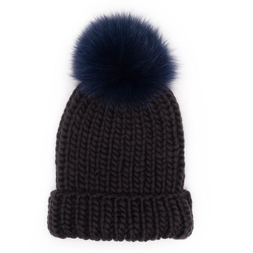 Black knit beanie with a blue fur pom-pom on a white background