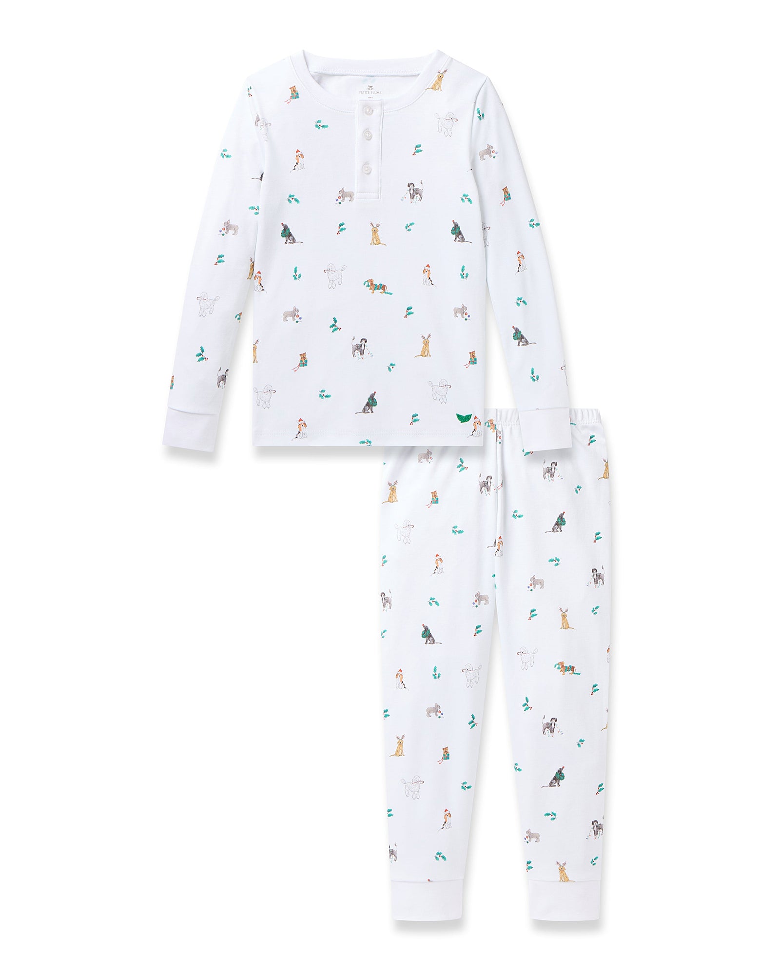 A young boy smiles, wearing the Petite Plume Kids Pima Snug Fit Pajama Set in Jingle Paws. This luxurious sleepwear features colorful small animal prints and provides comfort with its long sleeve top and pants as he stands barefoot against a plain background.