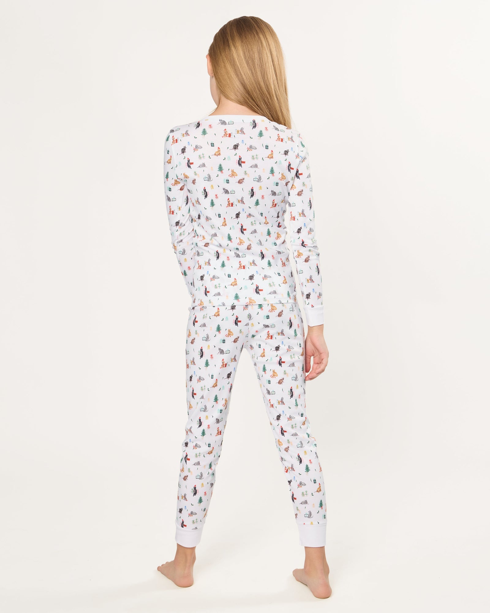 Kid's Pima Snug Fit Pajama Set in Merry Meow features a long-sleeve button-up top and matching pants with winter and holiday-themed prints of cats, trees, presents, and snowmen on a white background.