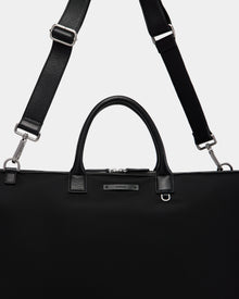 The Rudsak DUBLIN - 9324514 Black is a canvas leather weekender tote with silver hardware, two short handles, and an adjustable, detachable shoulder strap displayed against a plain light background.