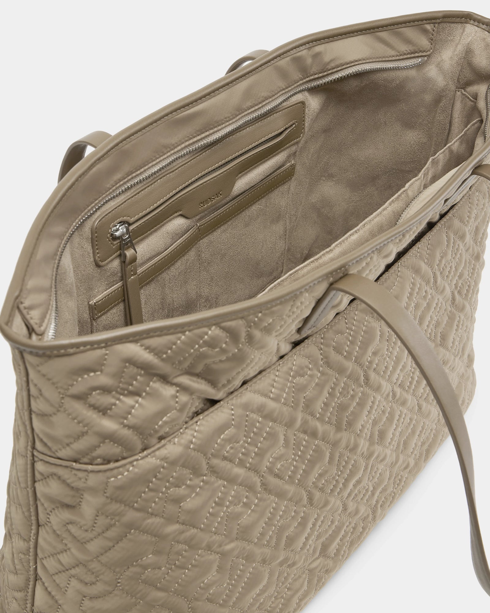 A close-up of the LIVORNO - L325007 Almond tote by Rudsak reveals its zippered pocket, card slot, and textured lining. This beige monogram bag features a leather strap and elegant stitching on its exterior.