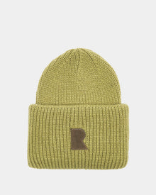 The Rudsak MURRAY - U423503 Light Olive is a unisex ribbed knit beanie with a wide folded brim and a front brown patch with a bold letter R, adding urban flair against a light gray background.