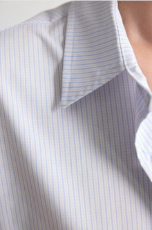 Close-up of a white shirt with blue stripes on a light gray background