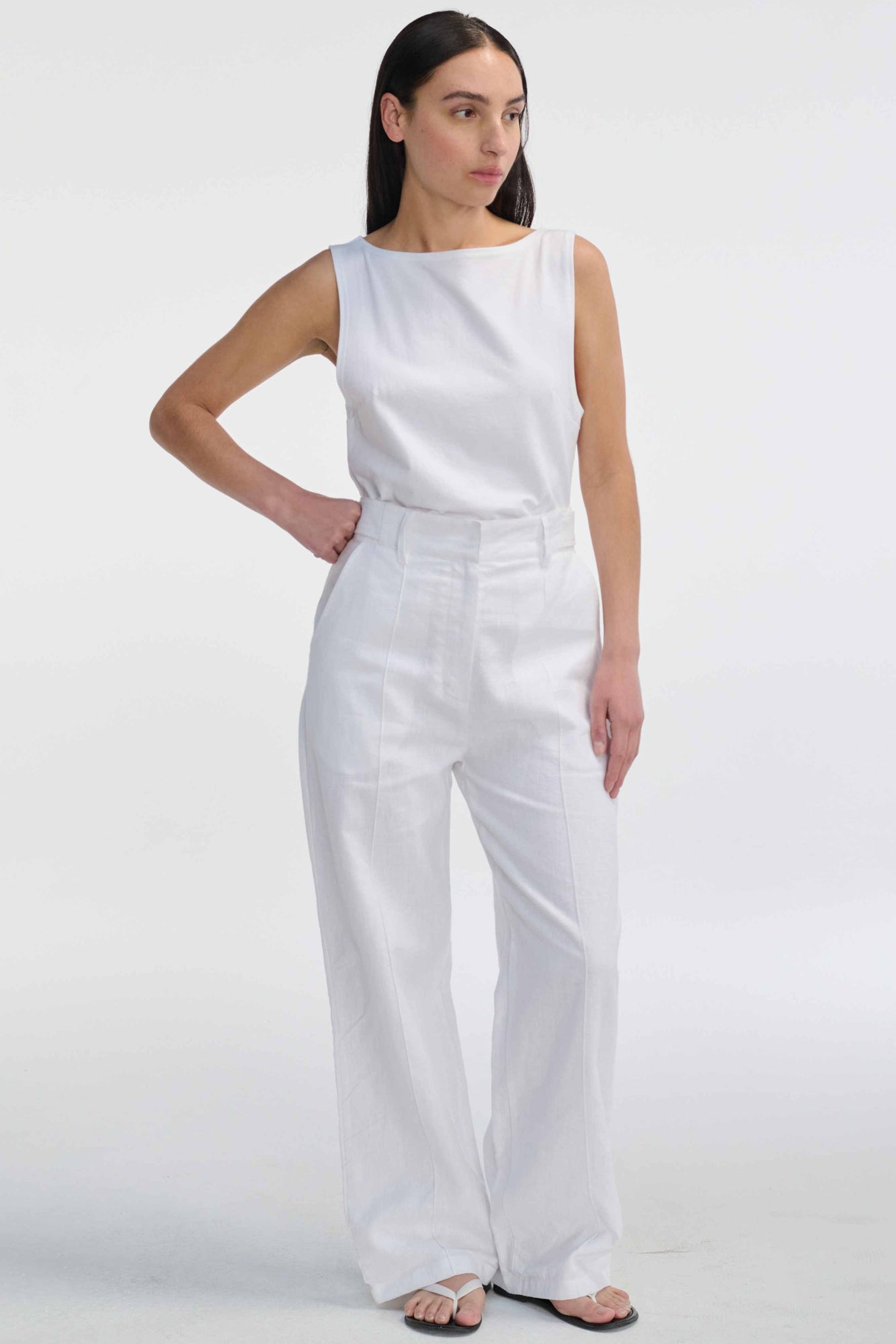 Woman wearing a white sleeveless top and wide-leg pants on a white background