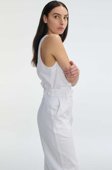 Woman wearing a white sleeveless top and pants on a light gray background