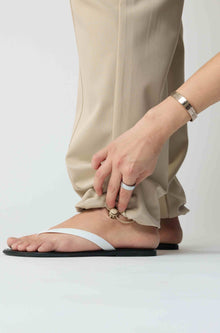 Woman wearing beige cargo pants and white flip flops on a light grey background