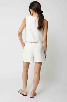 Woman wearing a white tencel vest and white linen shorts