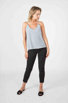 Woman wearing a light blue cami tank top and dark black pants