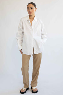 Woman wearing a white shirt and beige pants on a white background
