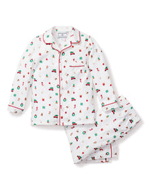 The Petite Plume Kids Twill Pajama Set in Winter Nostalgia showcases a festive winter print with red cars carrying Christmas trees, candy canes, stockings, and wreaths. This charming set includes a long-sleeve button-up top with red piping and matching pants, perfect for cozy holiday nights.