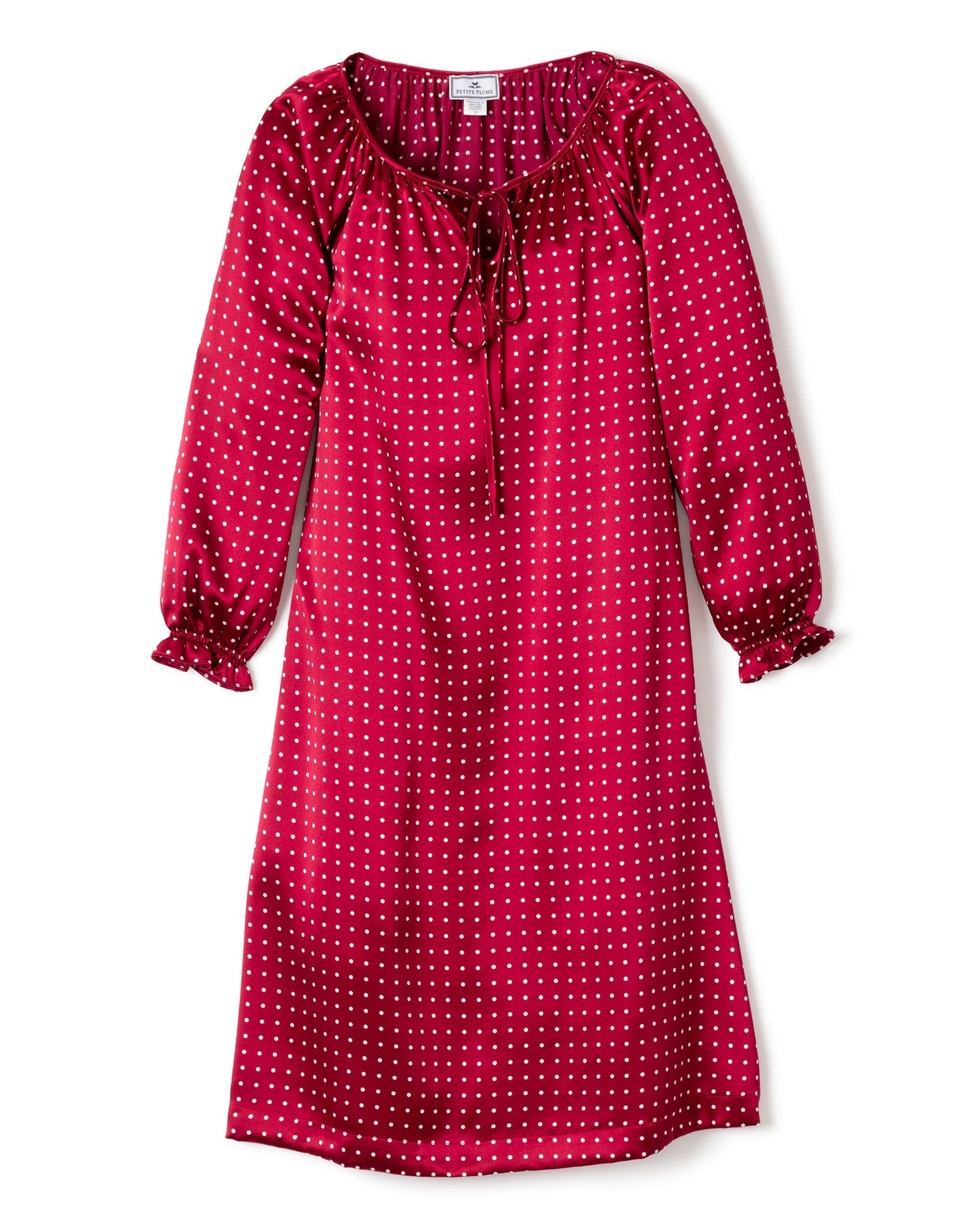 The Girls Silk Delphine Nightgown by Petite Plume in a Bordeaux polka dot design is perfect for cozy sleepwear. It features a gathered neckline with tie detail, slightly ruffled sleeve cuffs, and a relaxed straight cut that falls gracefully below the knees, combining elegance with comfort.