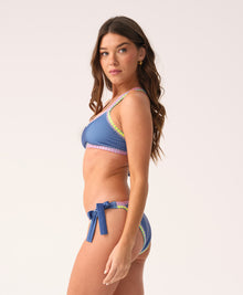 Woman wearing a blue bikini with colorful crochet trim on a white background