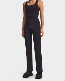 Wearing the ADRIANA - 8523550 Black by Rudsak, a sleeveless fitted top and high-waisted MVMT+ flared-leg leggings, paired with black athletic shoes—ideal for highlighting an active lifestyle against a white background.