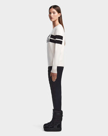 A woman stands in profile against a plain background, wearing Rudsaks ODESSA - 8523540 Iceland black quilted pants with platform boots and a soft-knit après-ski sweater for winter warmth.