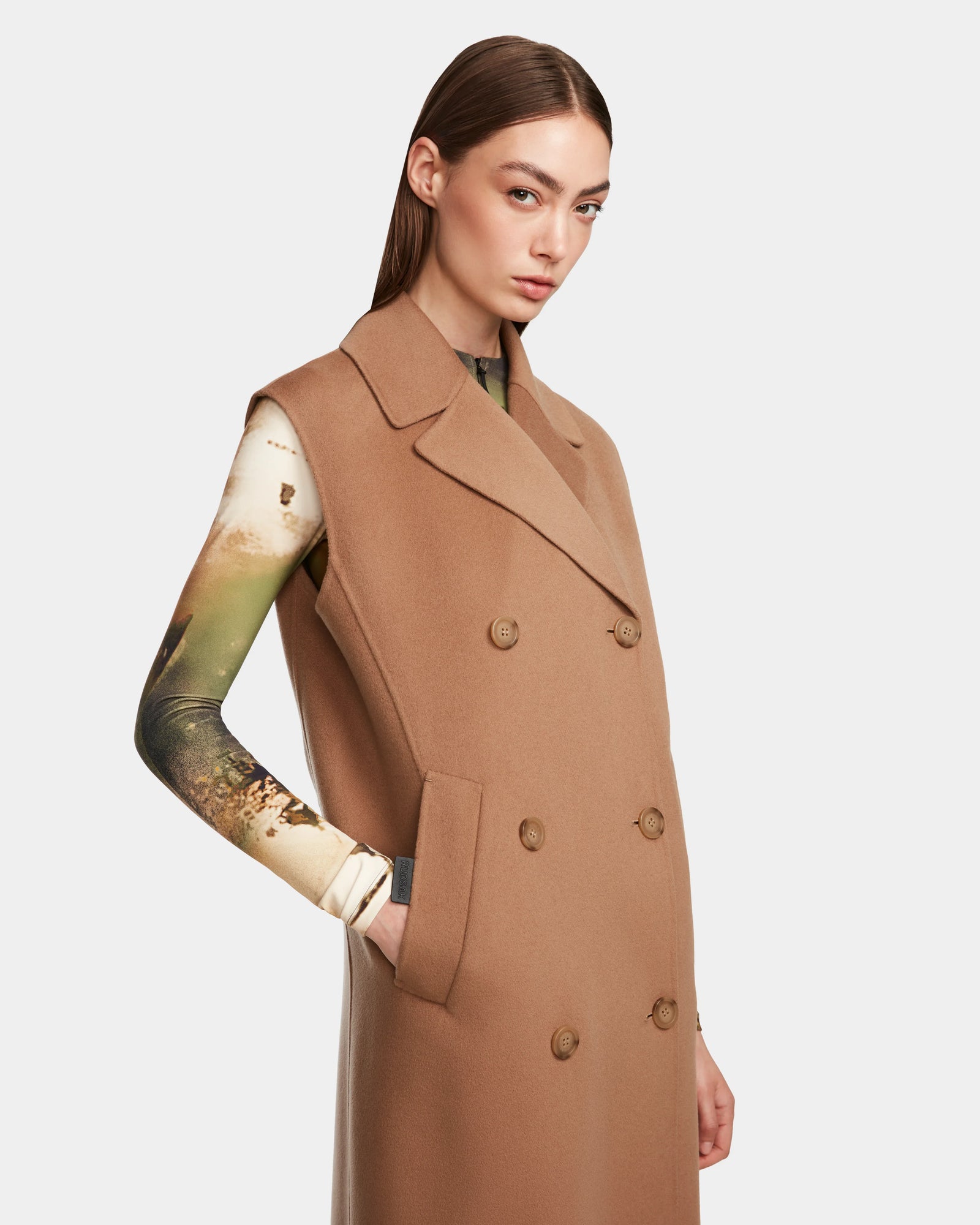 A woman in the Rudsak NOURA - 8124698 Camel, a knee-length, double-breasted vest.