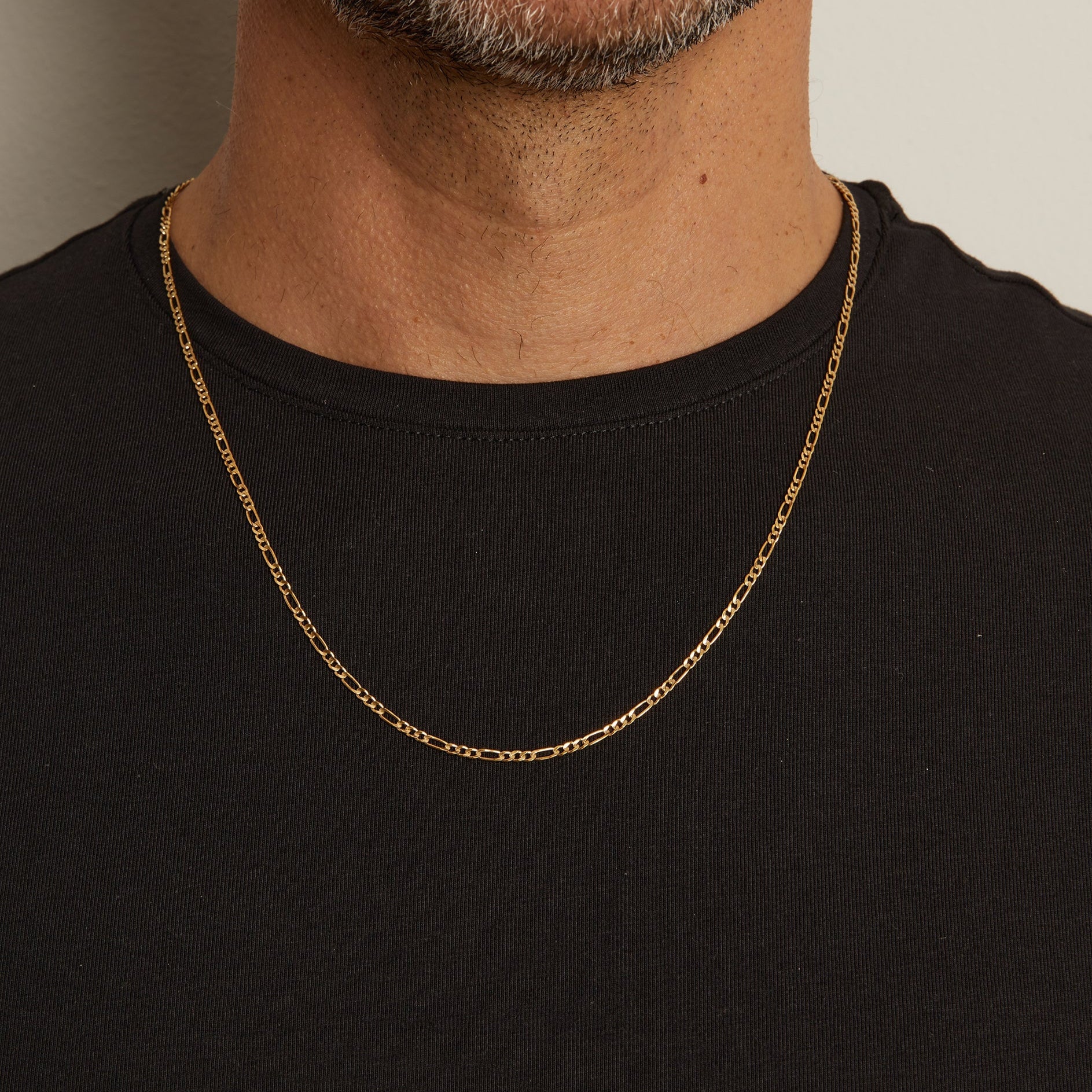 Model. Close up of man wearing gold chain necklace over a black t shirt