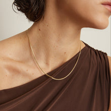 Model. Gold necklace worn by a person with a neutral background