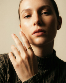 Close-up of a person wearing a ring on a neutral background