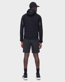 Wearing the JARRY - 6122007 BLACK men’s windbreaker puffer jacket by RUDSAK, a person stands facing away from the camera in black shorts, cap, socks, and sneakers against a plain white background—a sleek cold-weather essential.