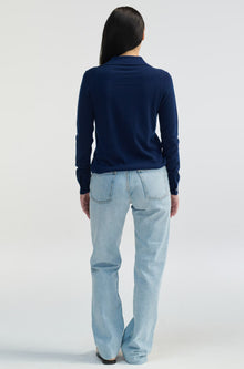 Person wearing a navy sweater and light blue jeans on a white background