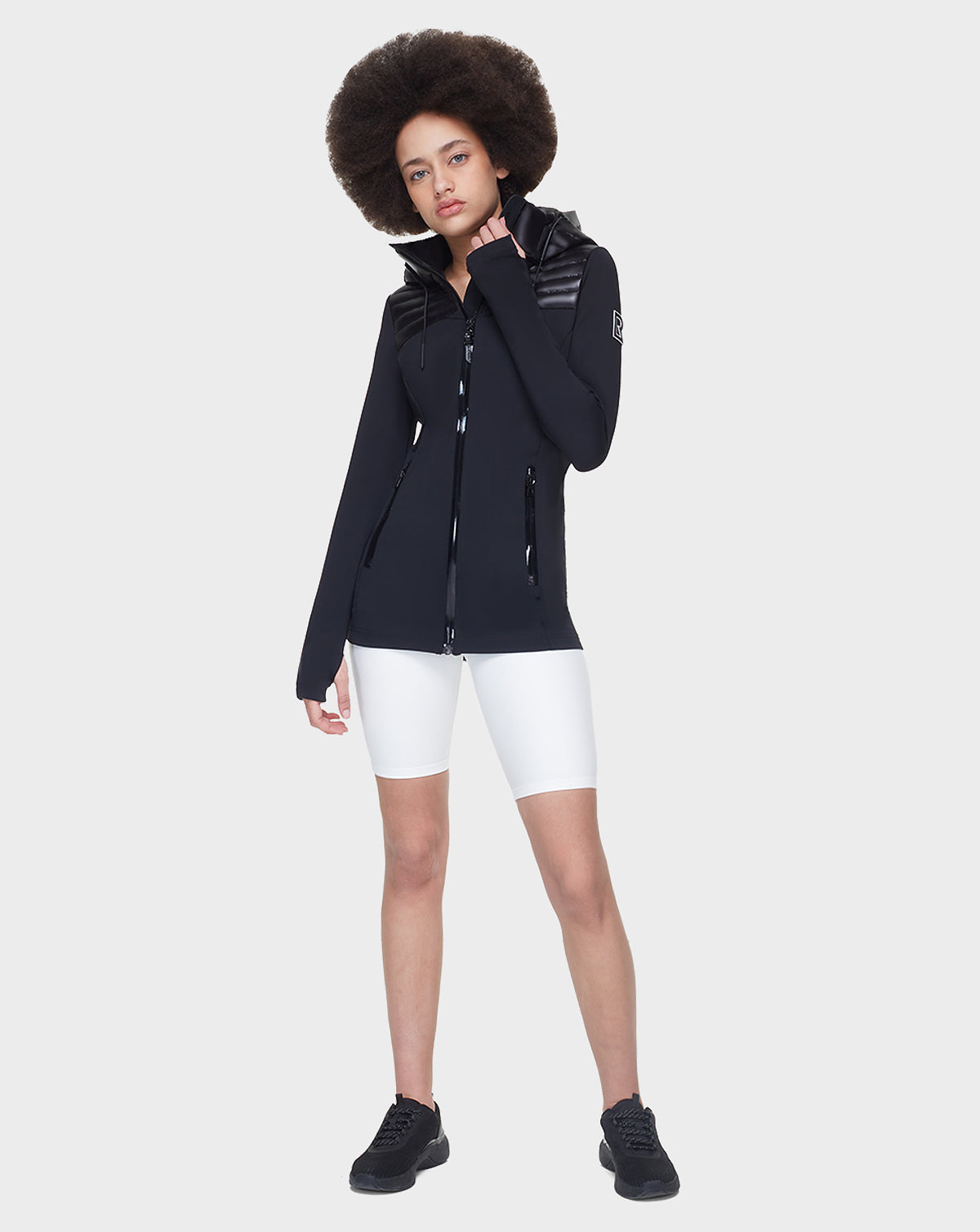 A woman poses for a picture wearing the Rudsak CAMIRA - 8122011 BLACK activewear jacket, which features waterproof zippers.